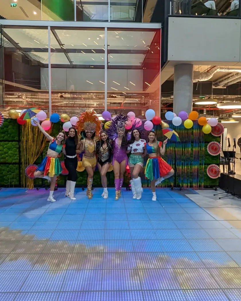 Brazil FitDance dancers in colourful costumes performing at a corporate event in an office atrium